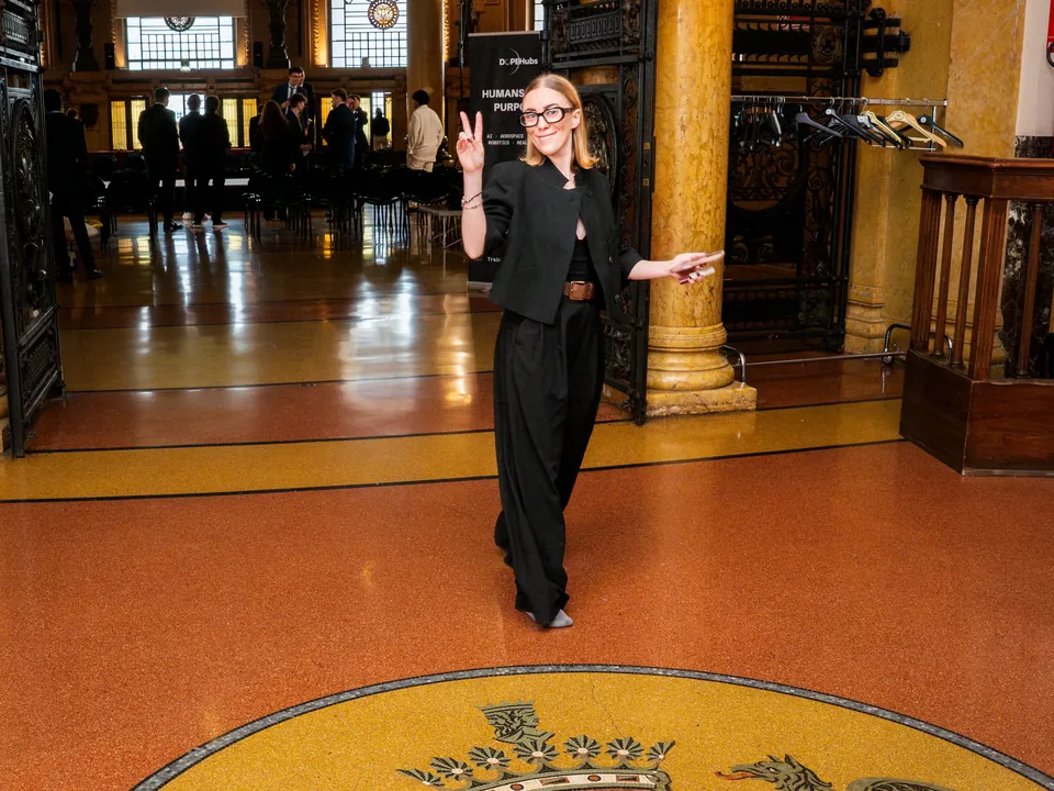 Paula Niubó aus der Kommunikation von DOPE macht das Victory-Zeichen in der Halle des Palazzo della Borsa, über dem Wappen von Genua