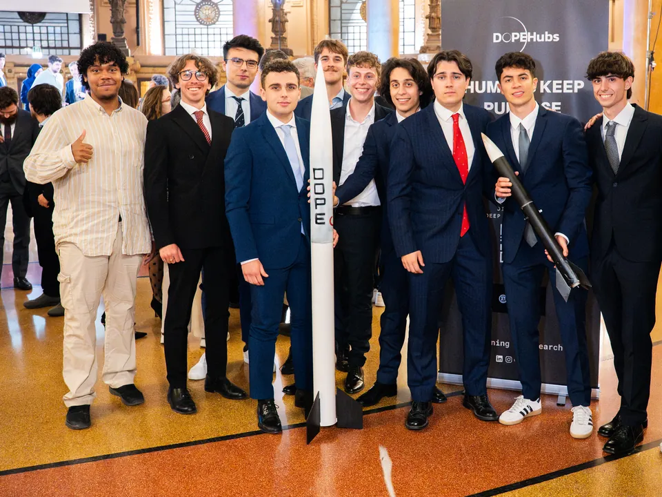 Das Raketenteam posiert neben einer Rakete, im Palazzo della Borsa